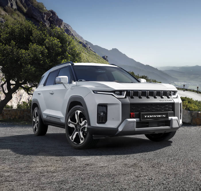 kgm-colombia-torres-hybrid Frente SUV premium KGM Torres Hybrid 2026 color blanco en mirador de montaña - Diseño robusto con parrilla icónica y luces LED en Colombia