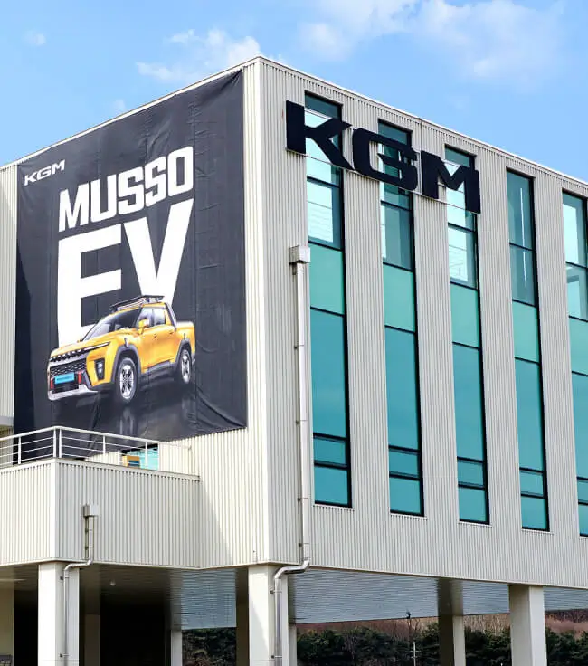 Edificio de la sede oficial de KGM Colombia con el logo corporativo de la marca y publicidad de la Musso EV.